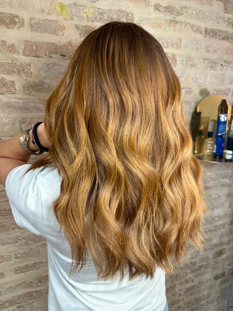 Onde morbide color caramello con riflessi ramati, viste da dietro nel salone