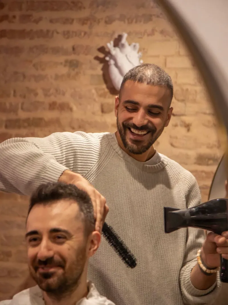 Enrico Cantore al lavoro con phon e spazzola su un cliente